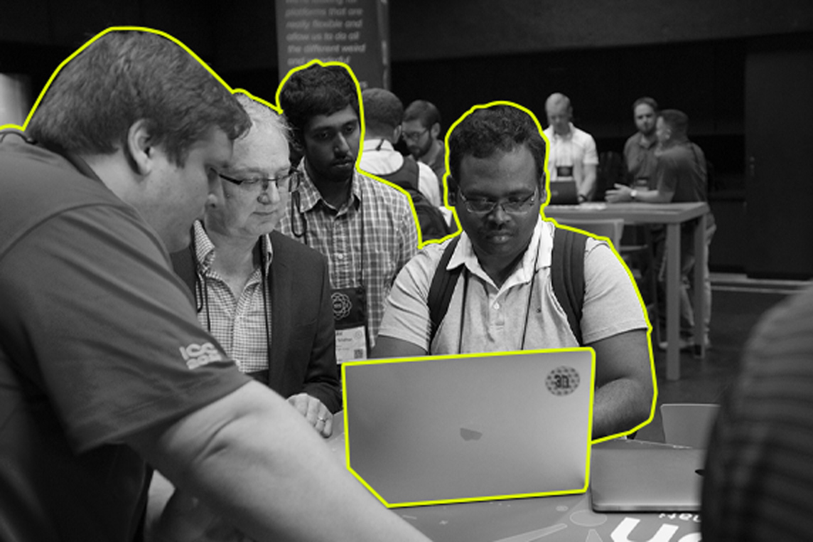 An Inductive Automation employee assists a conference attendee on his computer as others watch